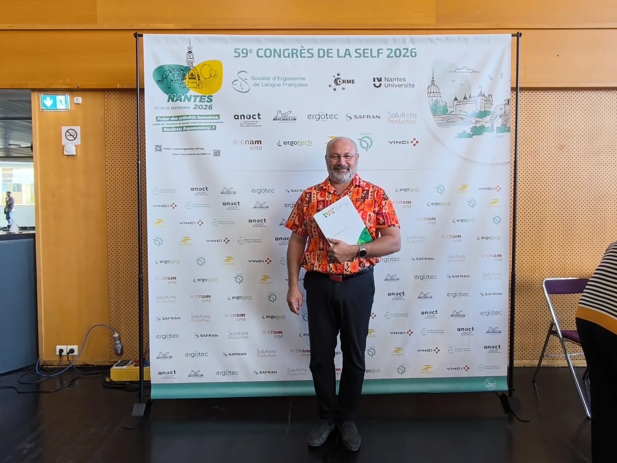Devant le mur des partenaires du 59e congrès de la SELF, attestation de présence en main